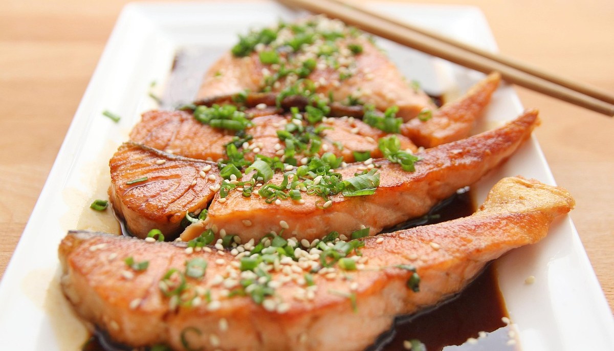 ごまとねぎをのせて焼いた鮭の切り身が、白い皿に並んでいる
